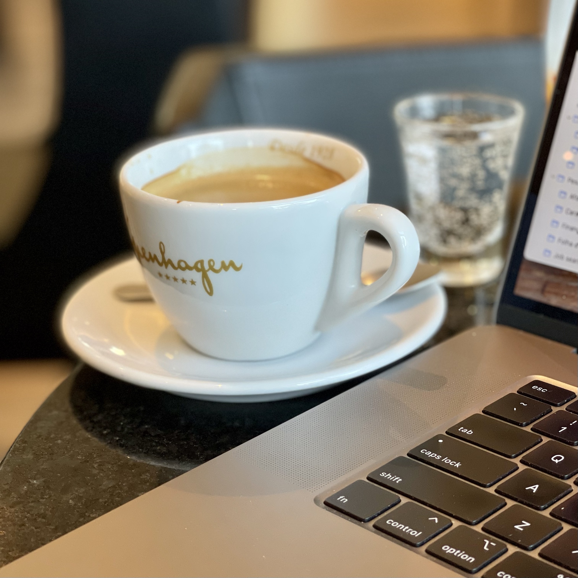 Una taza de café junto a una computadora de trabajo