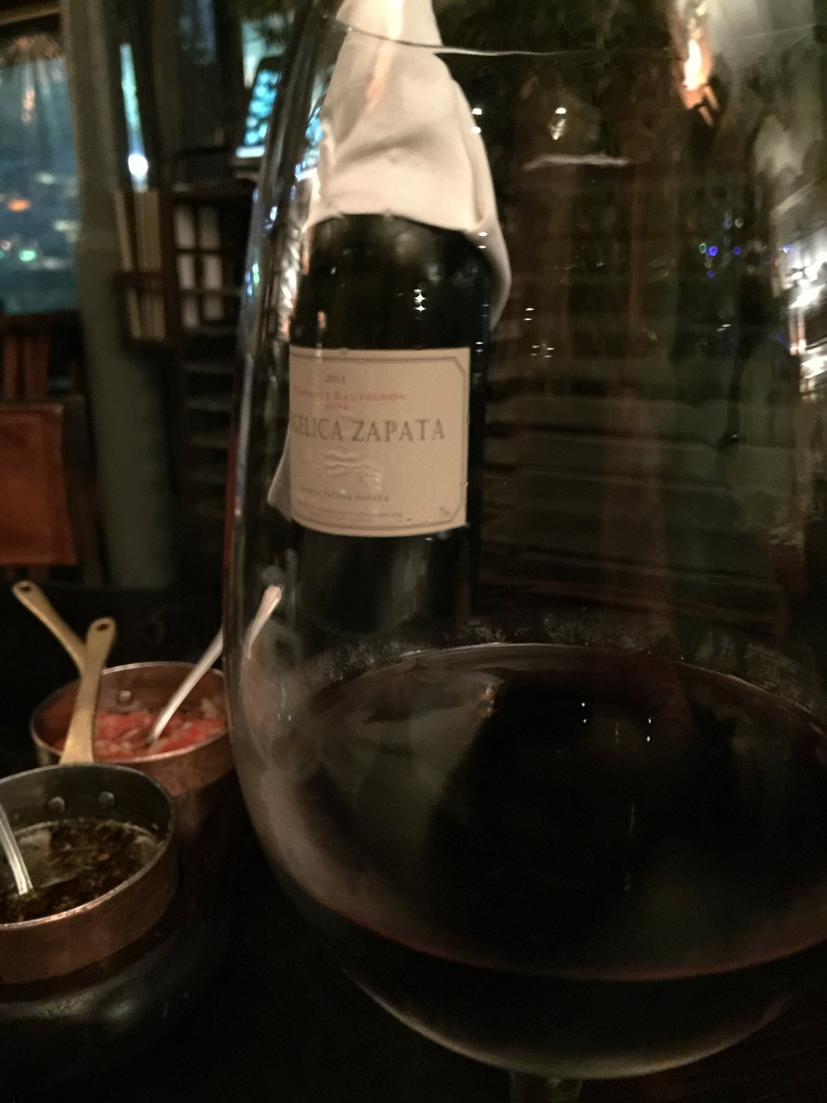 Una copa de vino tinto y una botella en la mesa de Cabaña Las Lilas