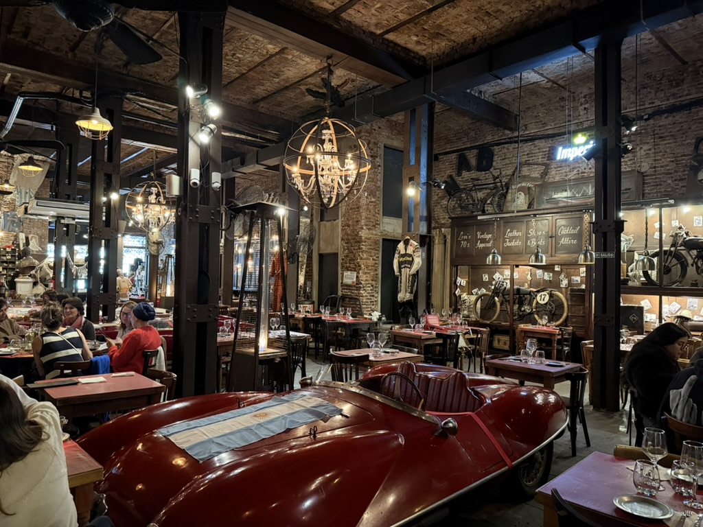 Automóvil clásico rojo entre mesas y antigüedades en Nápoles Bar