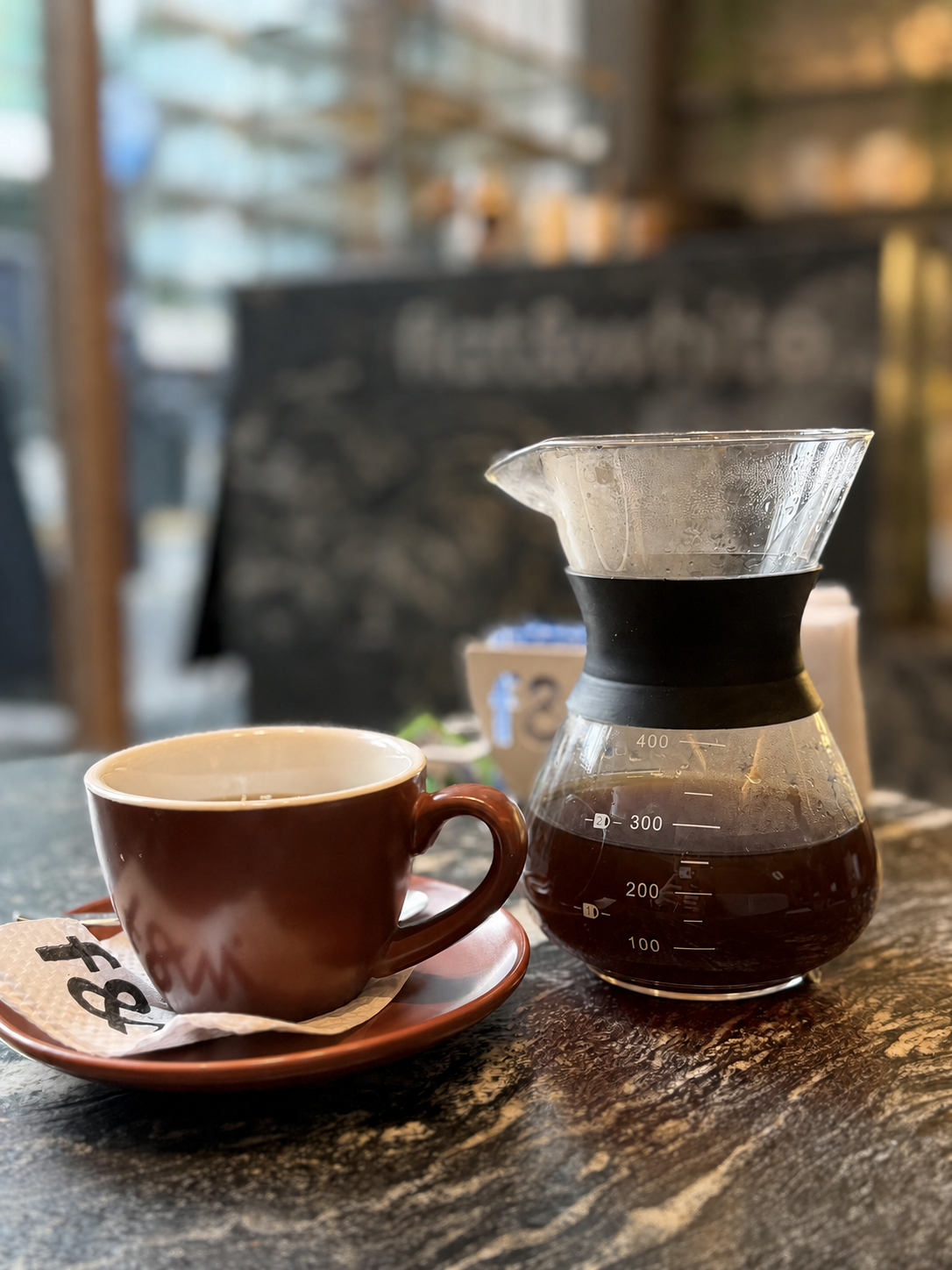 Taza marrón y jarra de café filtrado sobre una mesa en Flat and White, Buenos Aires
