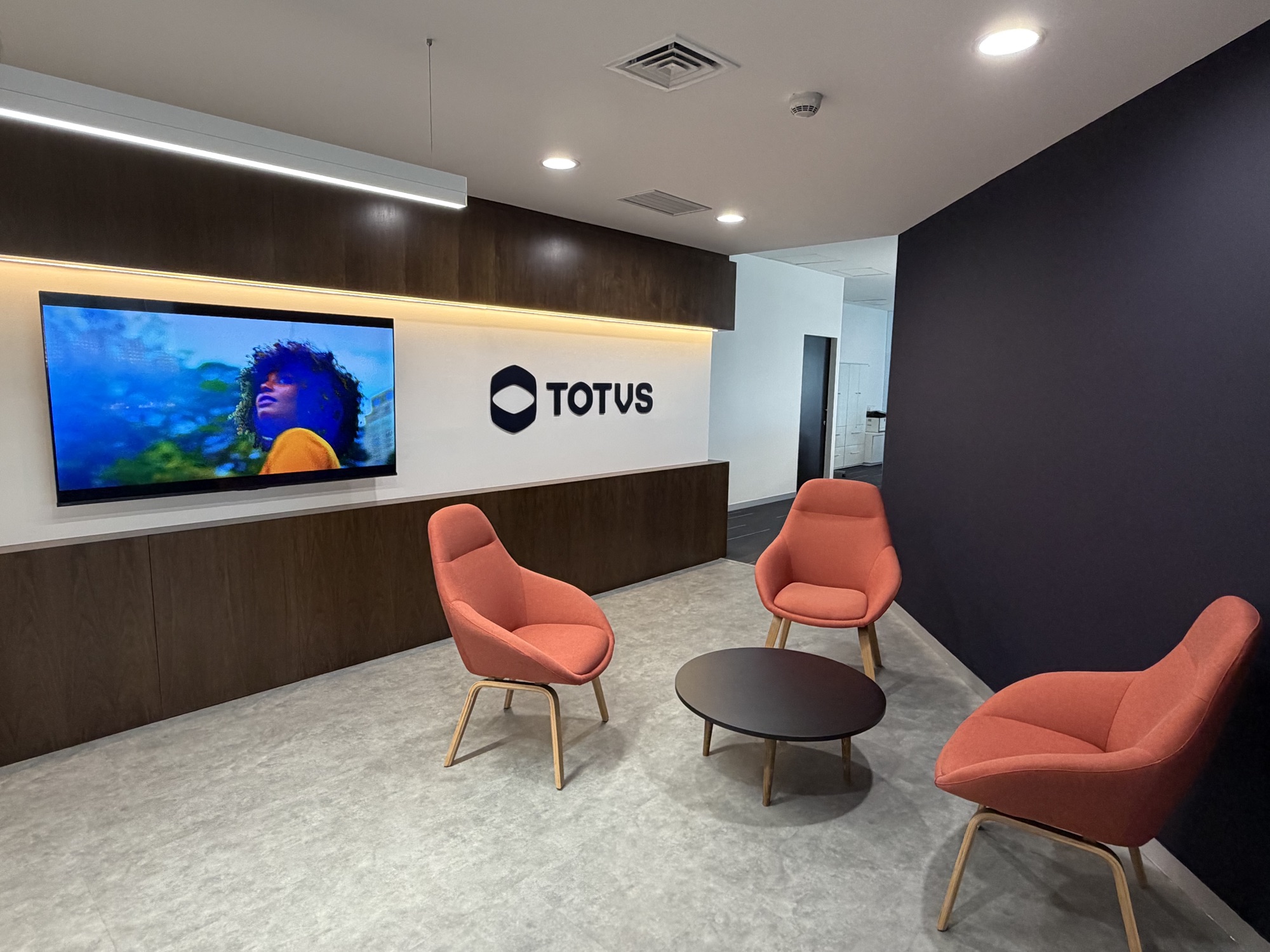 Recepción de TOTVS en Ciudad de México, con sillones naranjas y el logotipo de la empresa al fondo.