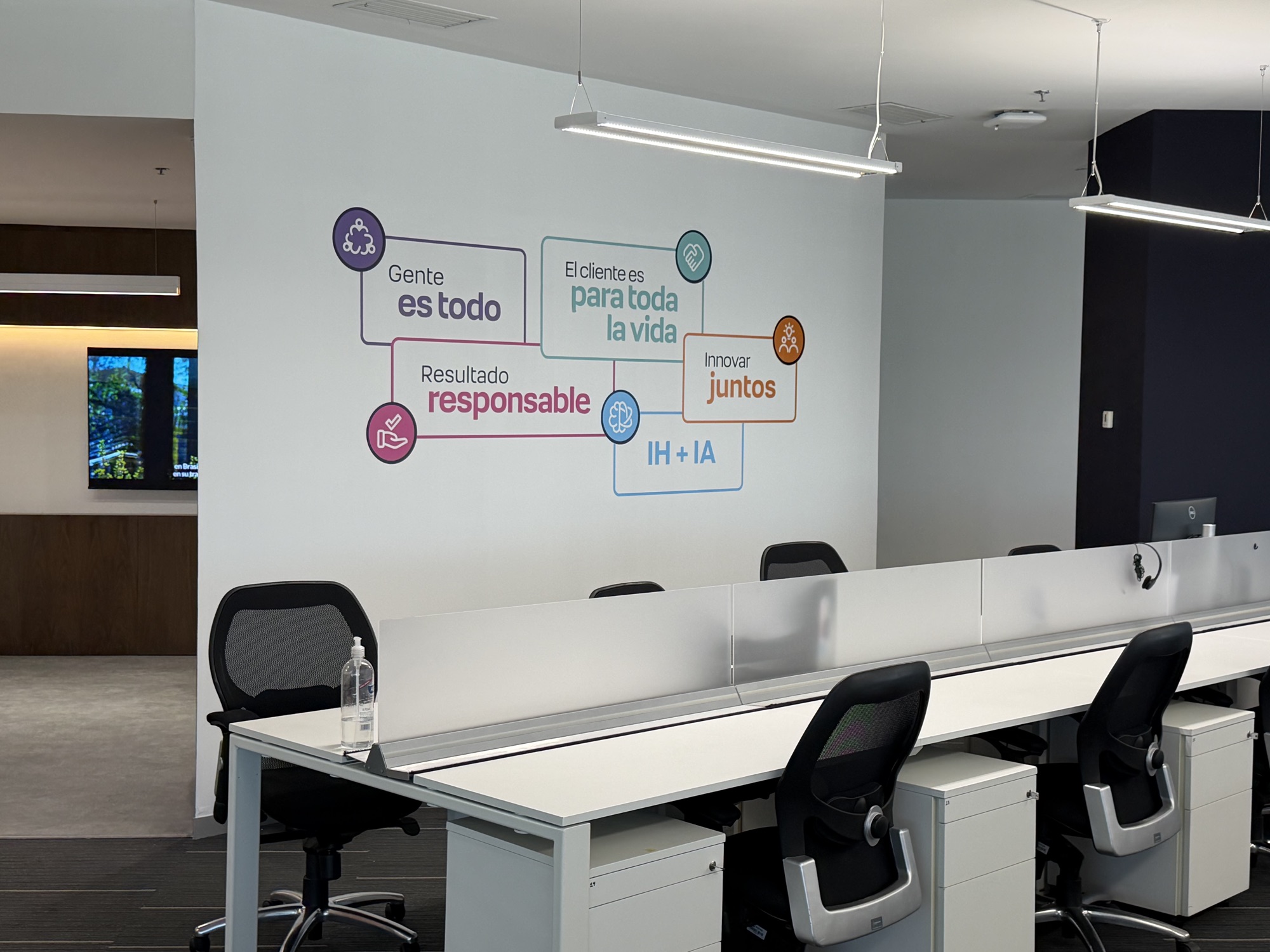Estaciones de trabajo junto a una pared con los valores de TOTVS: personas, clientes, responsabilidad, innovación e IH+IA
