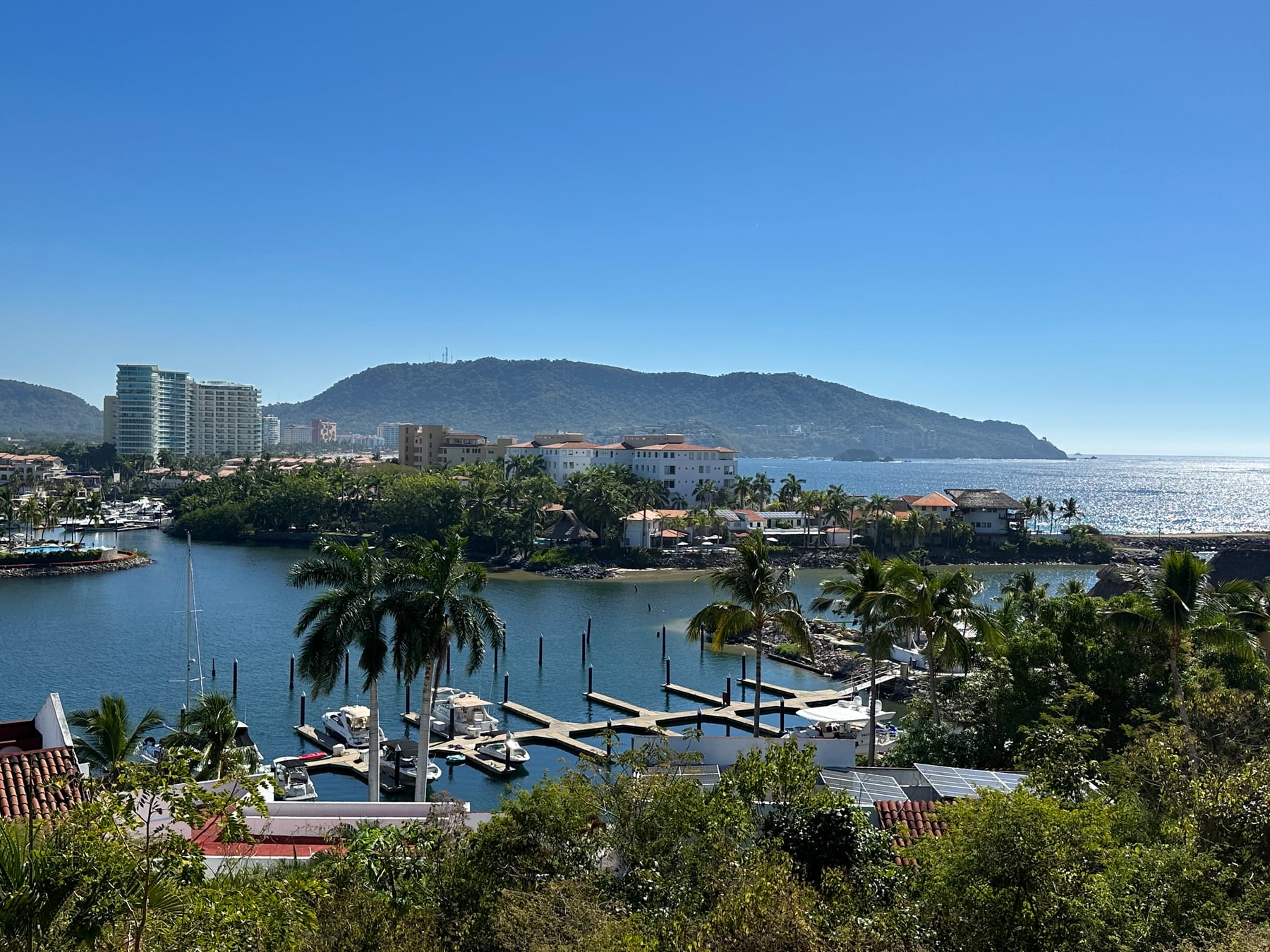 Vista panorámica de la marina de Porto Ixtapa, la costa y las montañas bajo un cielo azul