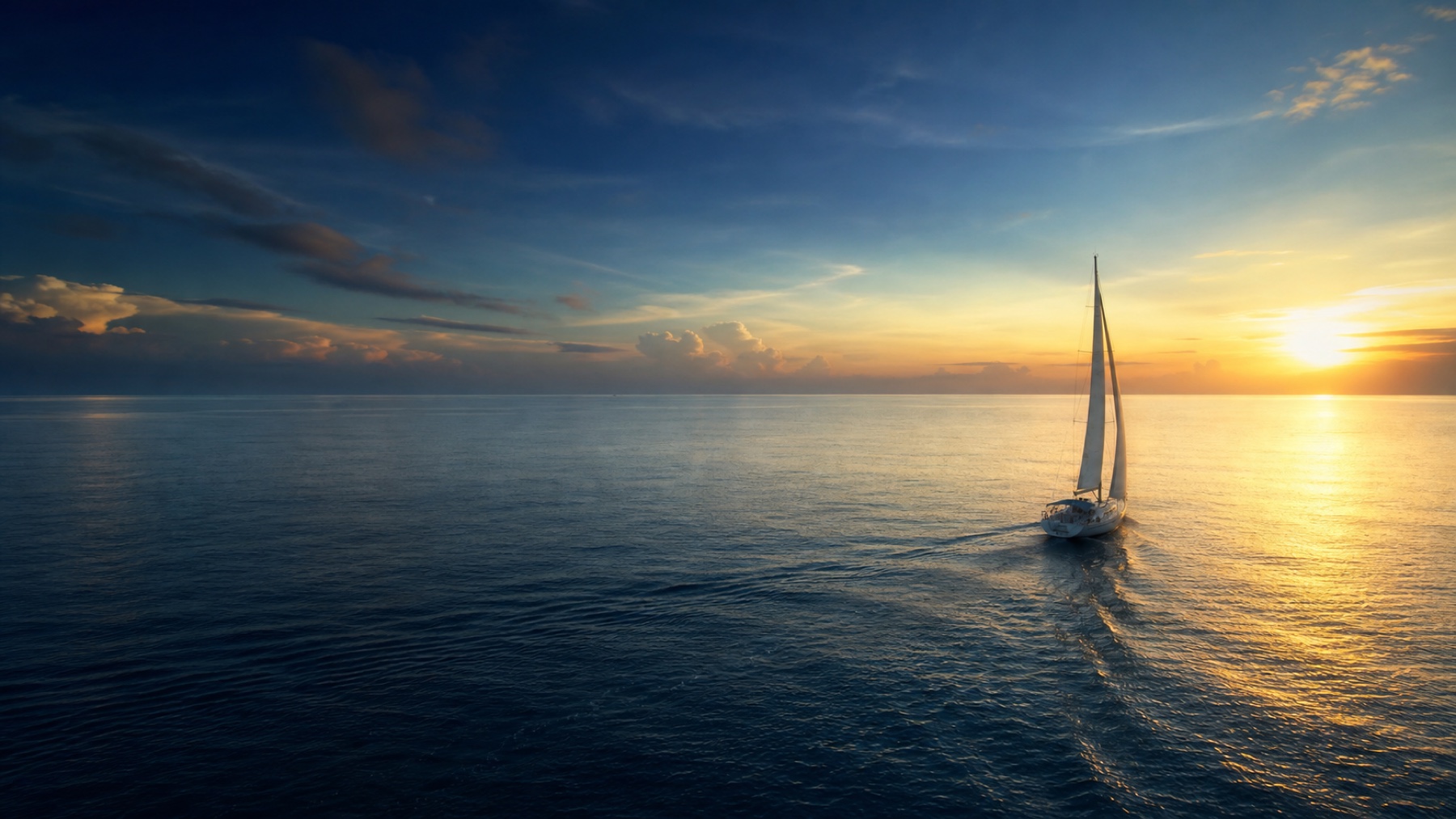 Velero navegando hacia el horizonte durante el atardecer