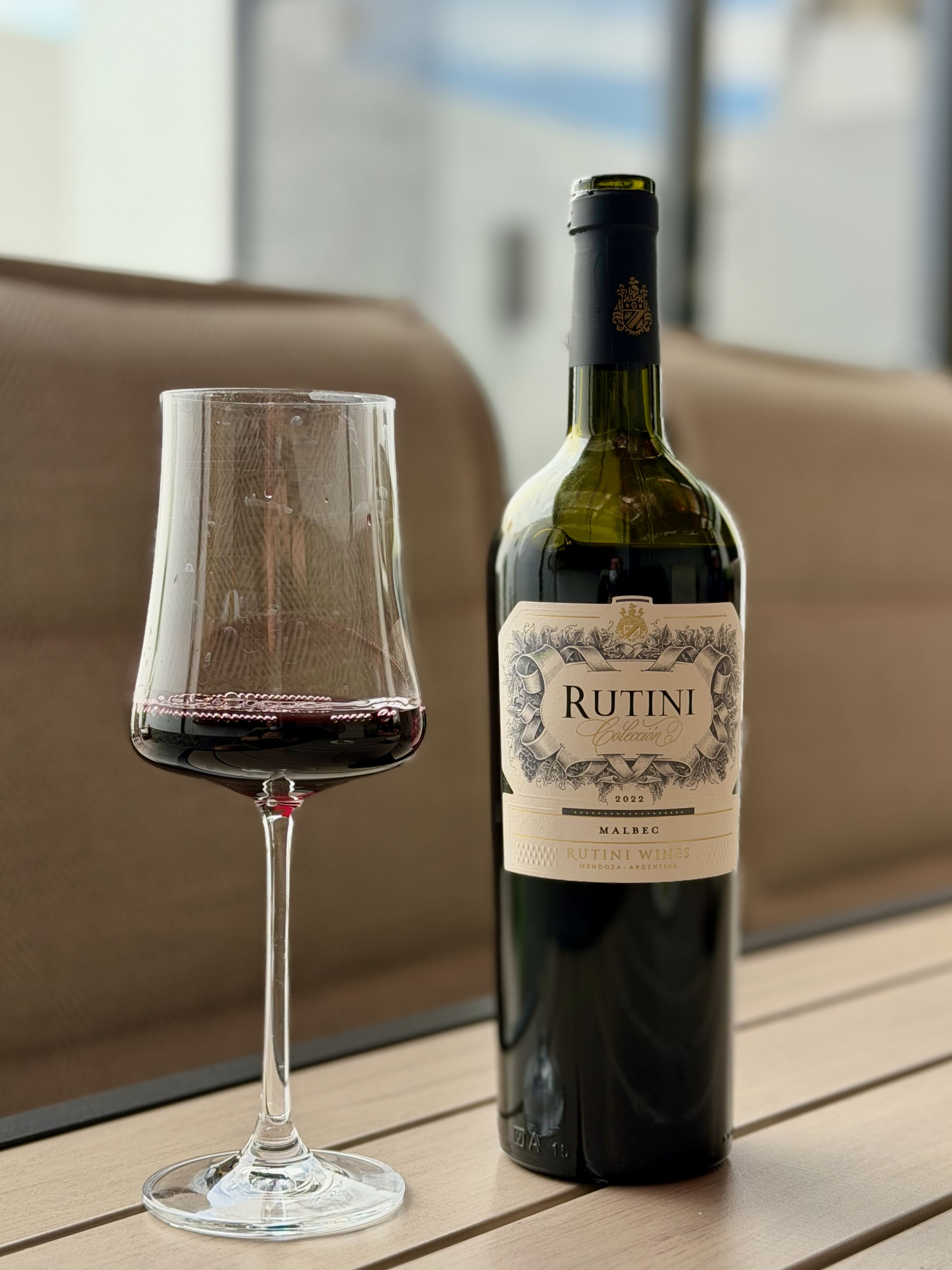 Botella de Rutini Malbec 2022 junto a una copa de vino tinto