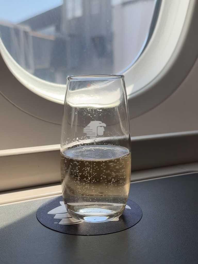 Copa de espumoso junto a la ventanilla de un vuelo de Aeroméxico