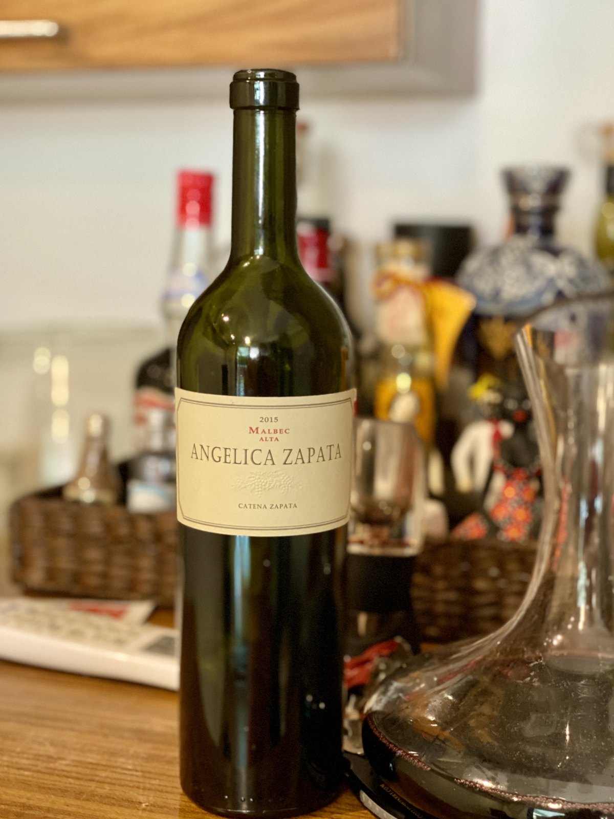 Botella de Angélica Zapata Malbec Alta 2015 junto a un decantador con vino tinto.