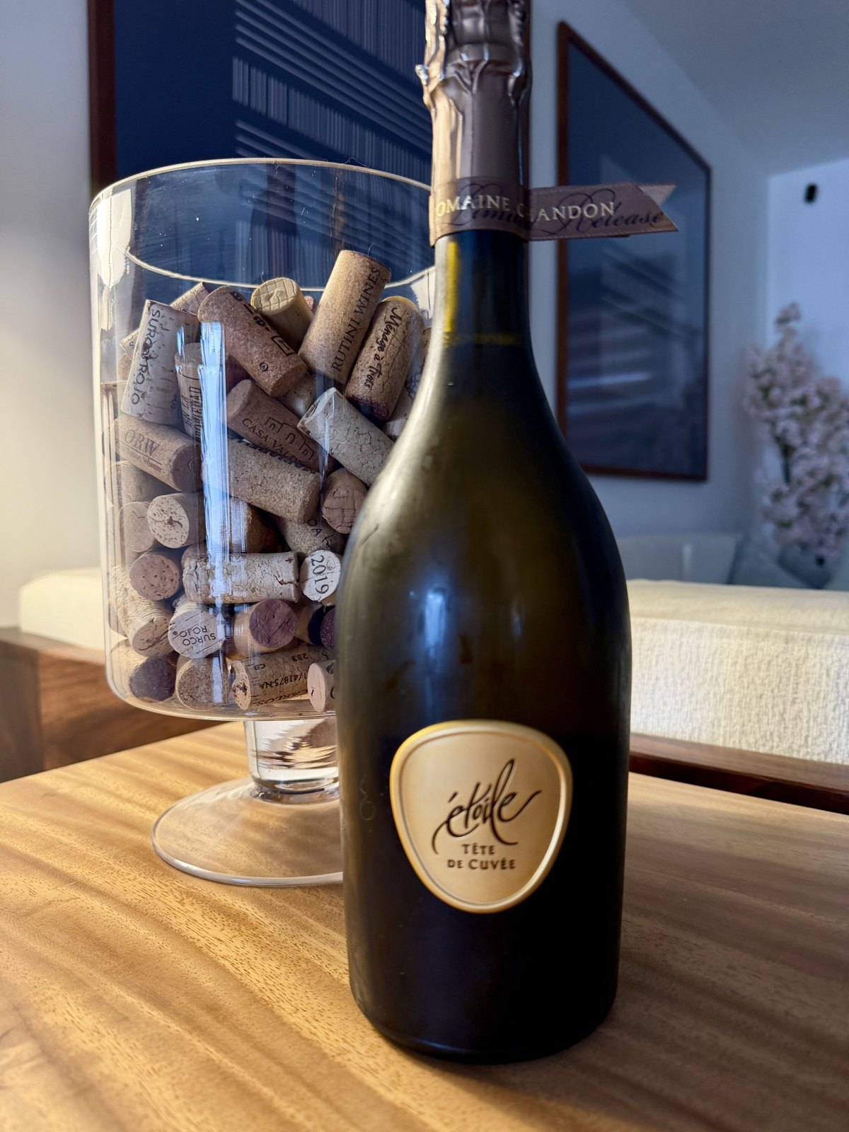 Botella de étoile Tête de Cuvée guardada en casa, junto a un recipiente con corchos.